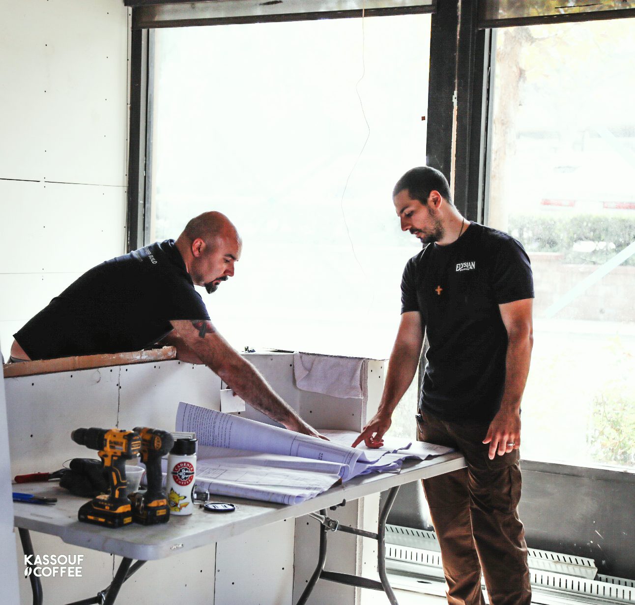 Nick reviewing architectural plans with a contractor inside a shop under construction